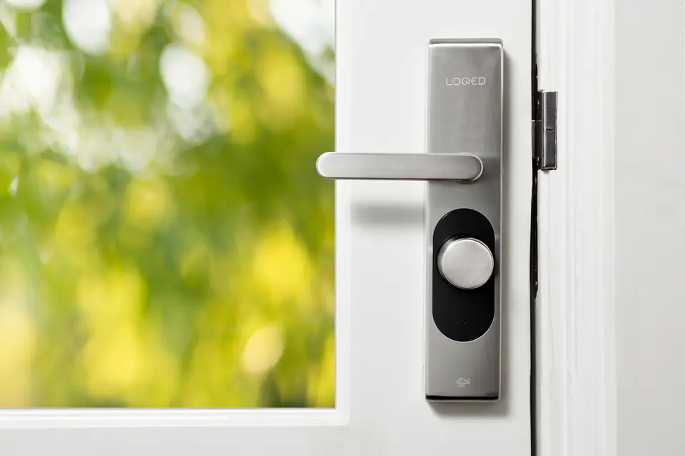 Brushed-steel smart lock and lever handle on a white glazed door