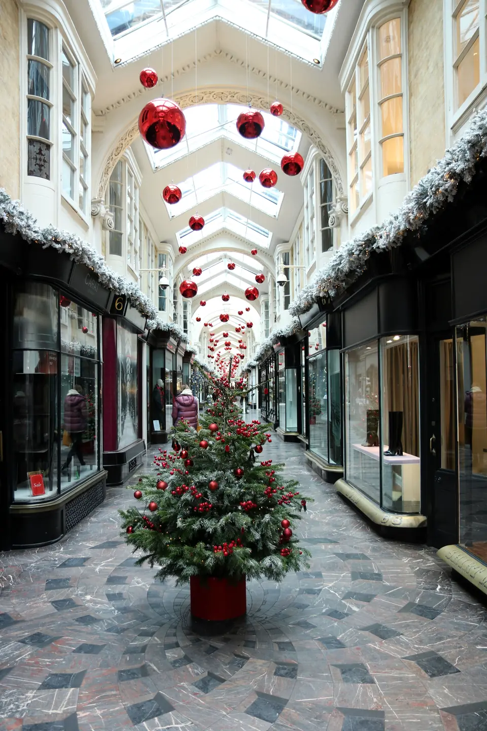 Shopping arcade decorated for Christmas, with a tree and red baubles