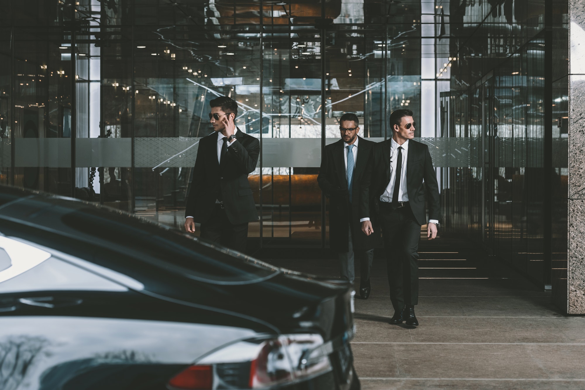 businessman and two bodyguards walking to auto